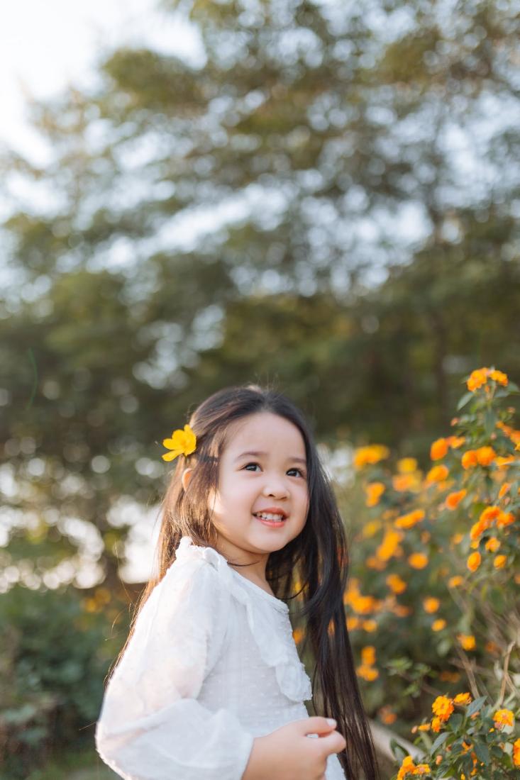 Bé gái cười bên hoa cúc vàng