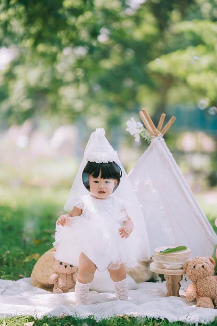 Bé mặc váy công chúa trắng bên lều dã ngoại