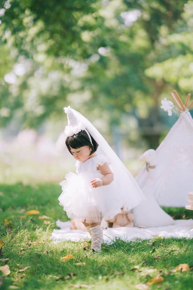 Bé đội mũ chóp trắng bên lều